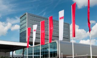 Red and white flags with the logo of RAI Amsterdam, in front of the RAI building