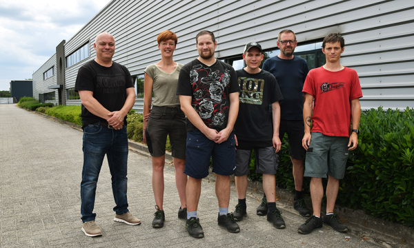 6 people posing for a picture in front of building