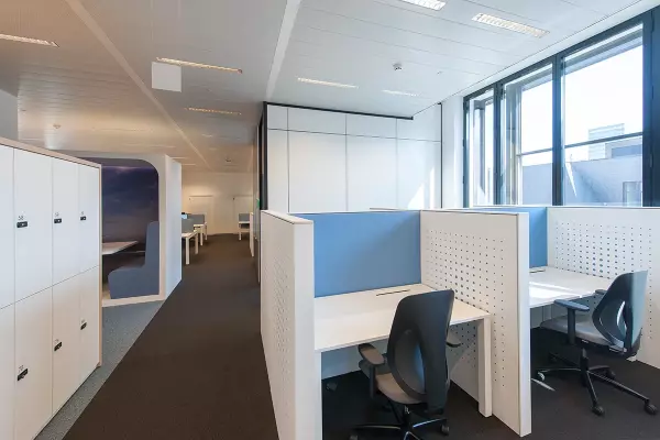 Individual desks with ergonomic office chair and light blue acoustic partition wall