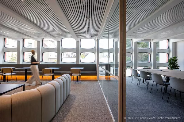 Modern office interior with an open space and a meeting room separated by a glass wall.